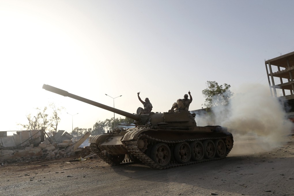 Fighters from the Benghazi Shura Council, which includes former rebels and militants from al Qaeda-linked Ansar al-Sharia, gesture on top of a tank next to the camp of the special forces in Benghazi. Photo: Reuters