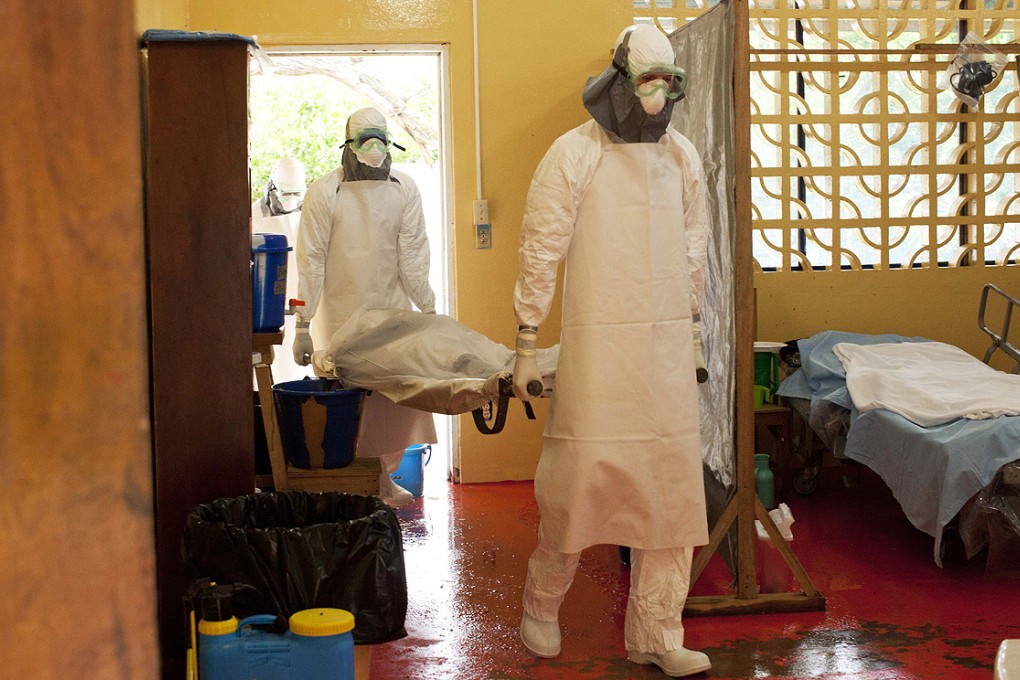 Dr Brantly (centre) wearing protective gear while treating an Ebola patient at ELWA Hospital in Monrovia prior to his contracting the disease. Photo: Reuters