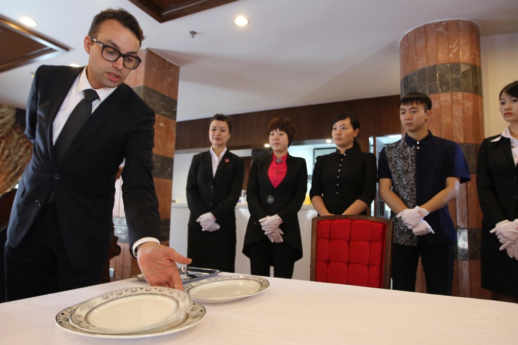 Instructor Francois Courberand shows students how to handle plates at a formal dinner for the well-to-do. Photo: Simon Song