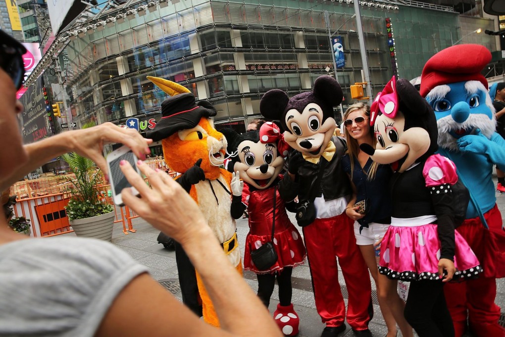 Costumed street performers pose with tourists for tips in Times Square. Sometimes the characters become aggressive. Photo: AFP