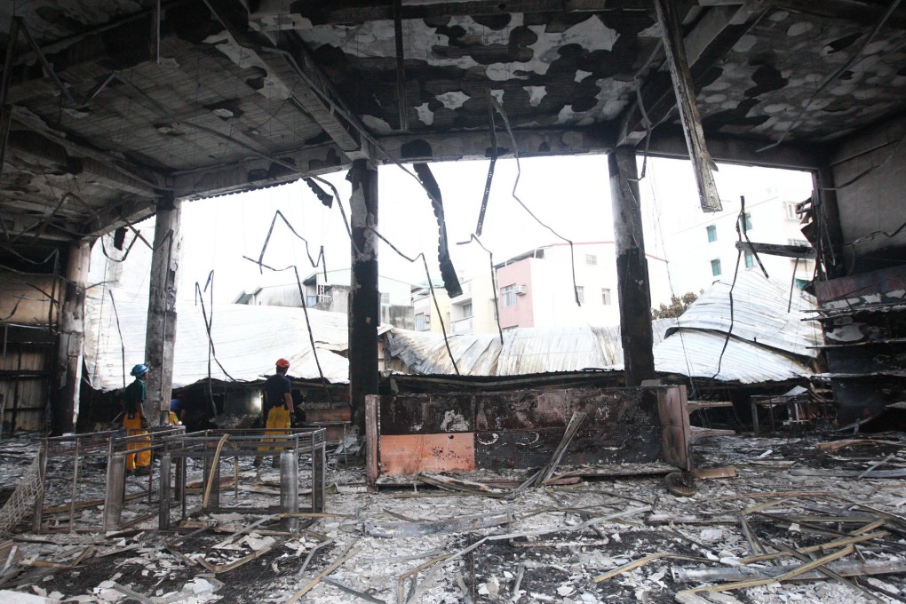 Workers inspect a damaged store. Photo: CNA