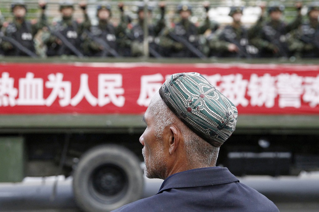 A Uyghur man looks on as a truck carrying paramilitary policemen travel along a street during an anti-terrorism oath-taking rally in Urumqi. Photo: Reuters