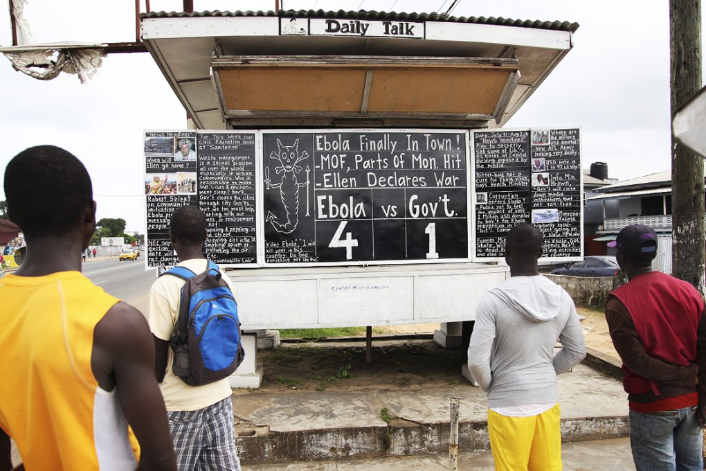 Liberians read The Daily Talk chalk board carrying stories of the deadly Ebola virus on a street corner in Monrovia. Photo: EPA