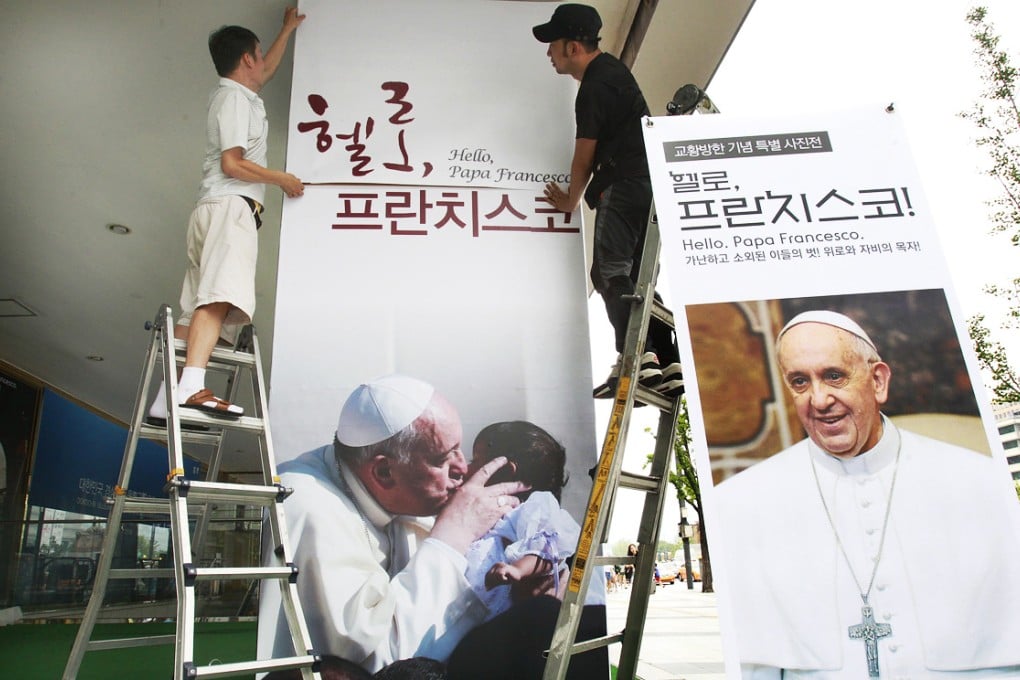 Workers set up a poster of Pope Francis's photo exhibition "Hello, Pope Francis!" at the Sejong Culture Centre in Seoul, South Korea. Photo: AP