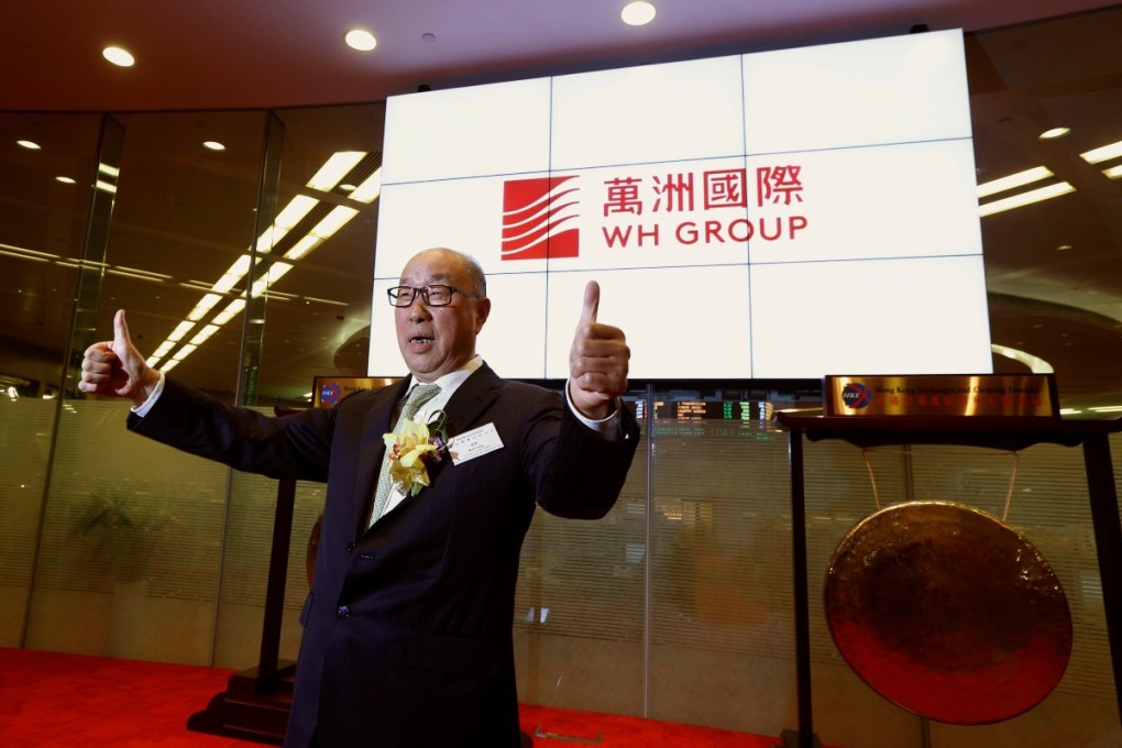 WH Group chairman and chief executive Wan Long poses in front of the company logo during the debut of the company at the Hong Kong Stock Exchange. The company was trading at HK$6.59 at 10.31am on Monday. Photo: Reuters