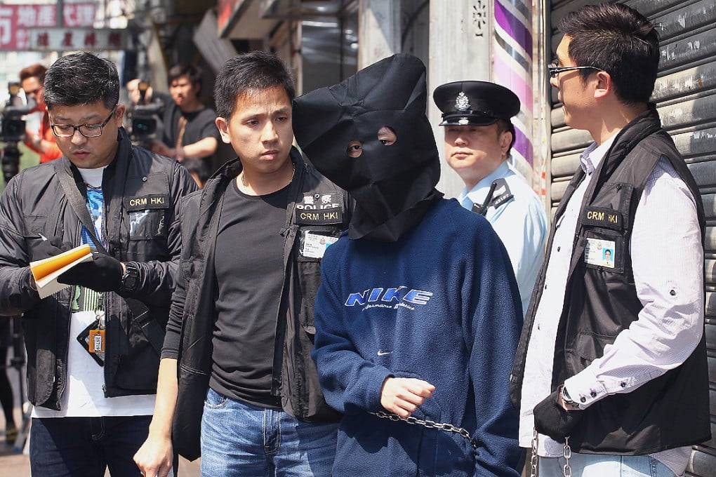 One of the suspects Henry Chau is escorted by police officers to a flat at Kok Cheung Street in Tai Kok Tsui in March, 2013. Photo: Felix Wong