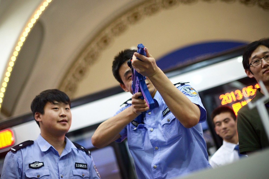 A police officer (centre) aiming with a telescopic sight fitted to a gun model at an exhibition. Among the new gadgets on show by China North Industries Group are scratch-proof gloves and gold crash-proof railings. Photo: AFP