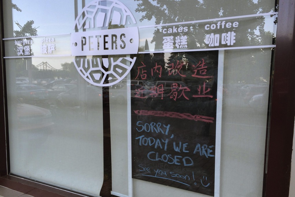 A notice indicating the closure of the shop is placed behind the window of the coffee shop owned by Canadian couple Kevin Garratt and Julia Dawn Garratt in Dandong. Photo: Reuters