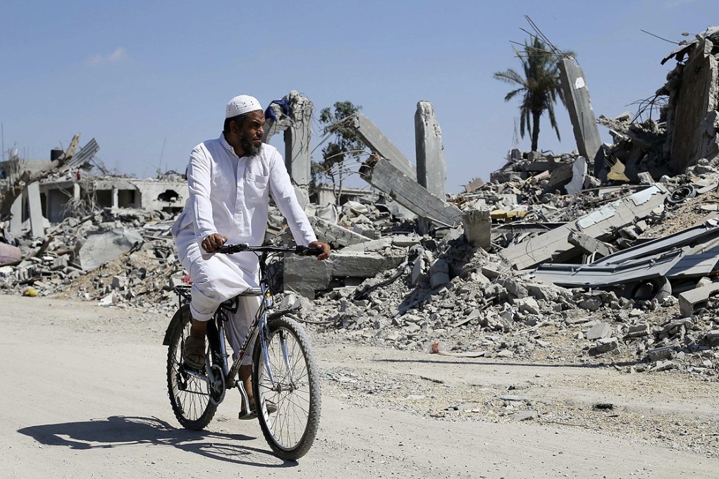 A Palestinian man rides his bicycle past the ruins of destroyed houses in the southern Gaza Strip on Wednesday. Photo: Reuters