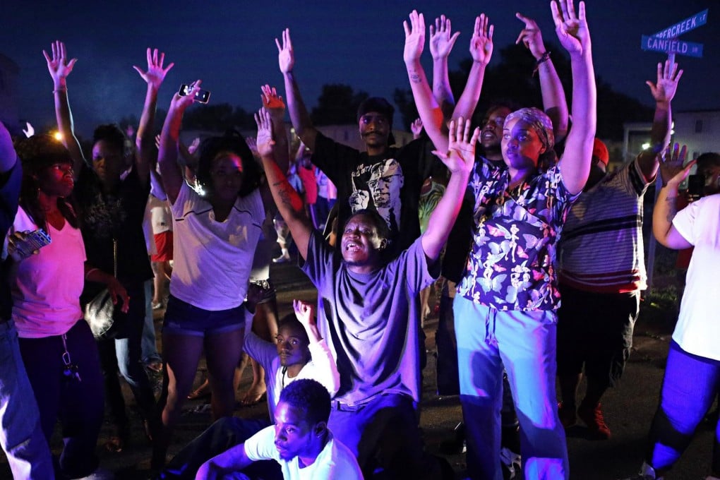 "Don't shoot us" chant protesters as they confront police officers arriving to break up the crowd after the shooting in Ferguson. Photo: MCT