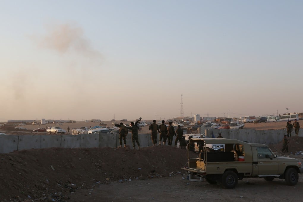 Kurdish Peshmerga fighters stand guard as smoke rises after airstrikes targeting Islamic State militants outside of the city of Arbil in northern Iraq. Photo: AP