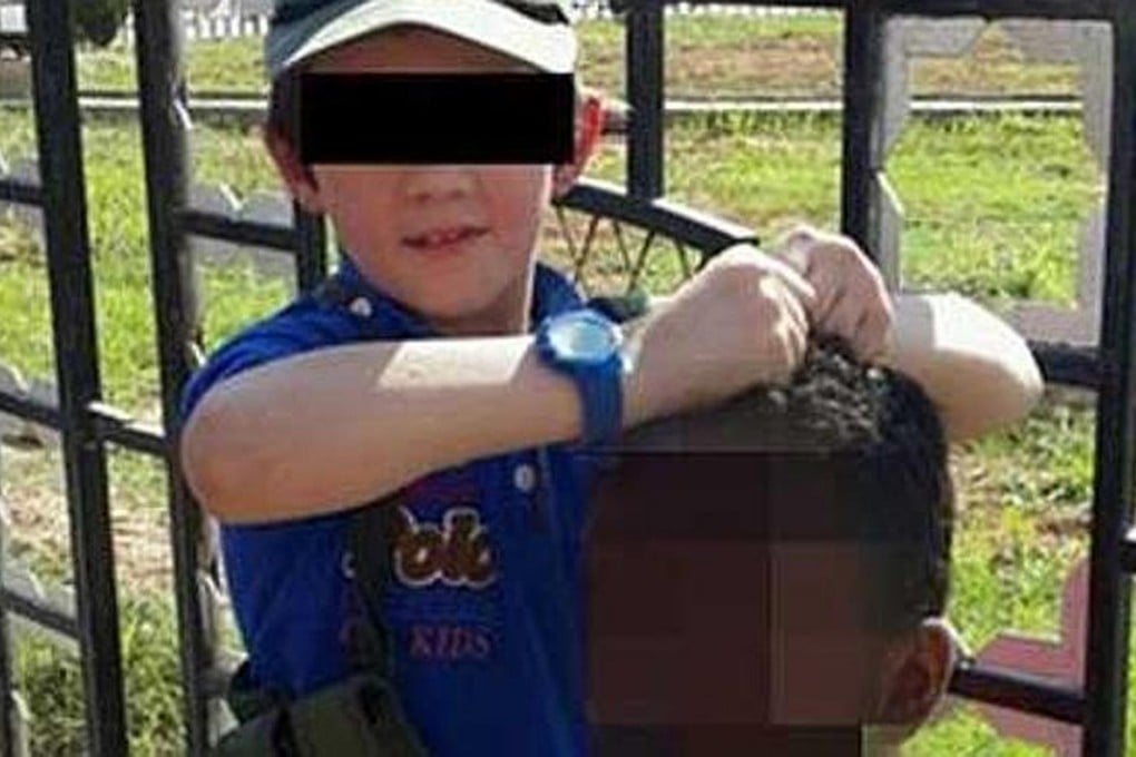 The boy holds the head of a Syrian soldier. Photo: Twitter