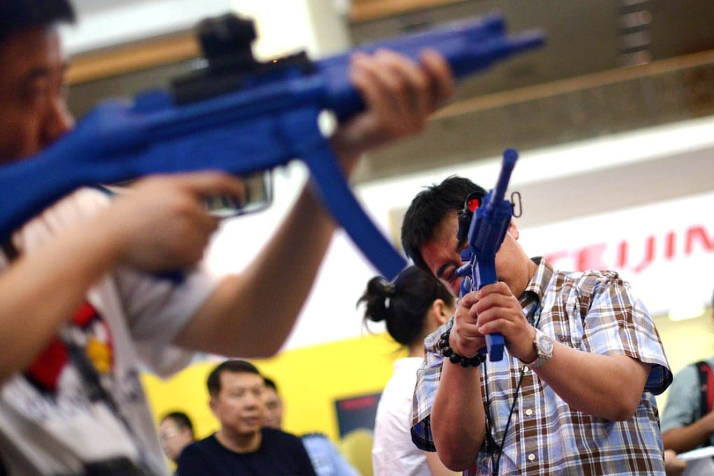 Visitors hold gun models at a rare firearms exhibition in China. Photo: AFP