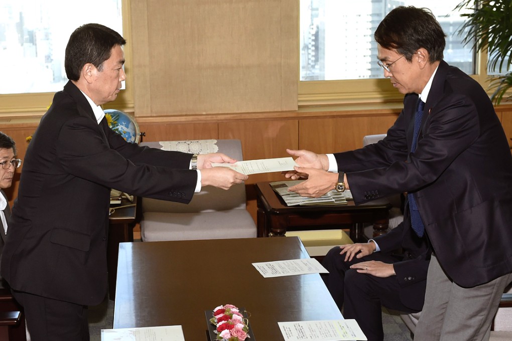 Miyagi Governor Yoshihiro Murai (left) hands over a document to Environment Minister Nobuteru Ishihara in Tokyo on August 7, 2014, to accept government-funded research in the prefecture to find a candidate site for the final disposal of some of the radiation-tainted waste from the Fukushima nuclear disaster. Photo: Kyodo