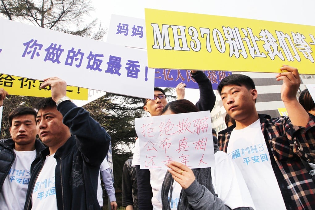 Relatives of the MH370 passengers holding placards and banners, with chinese characters to express their good wishes to their loved ones on the plane and requesting the truth from Malaysia government, at the Malaysia Embassy in Beijing. Photo: Simon Song