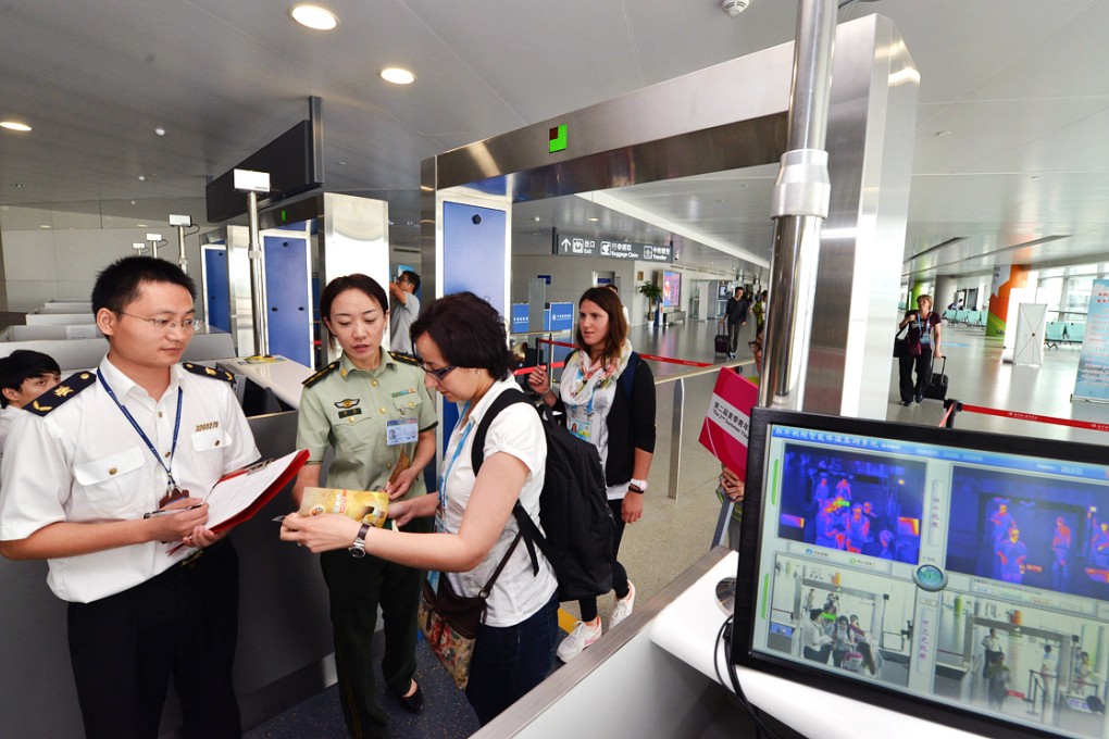 Customs and quarantine staff members hand out brochures about preventing Ebola virus disease to passengers arriving at the airport in Nanjing. Photo: Xinhua