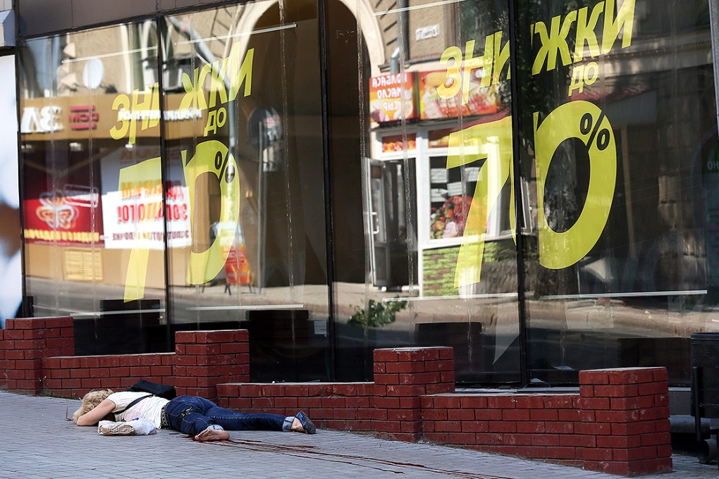 A wounded woman lies on the street after a mortar attack in the centre of Donetsk. Photo: EPA