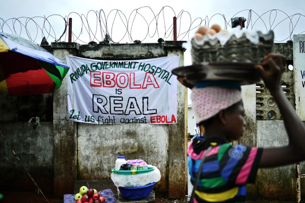 A girl walks past a sign warning of Ebola dangers near a clinic in Freetown, Sierra Leone. Photo: AFP
