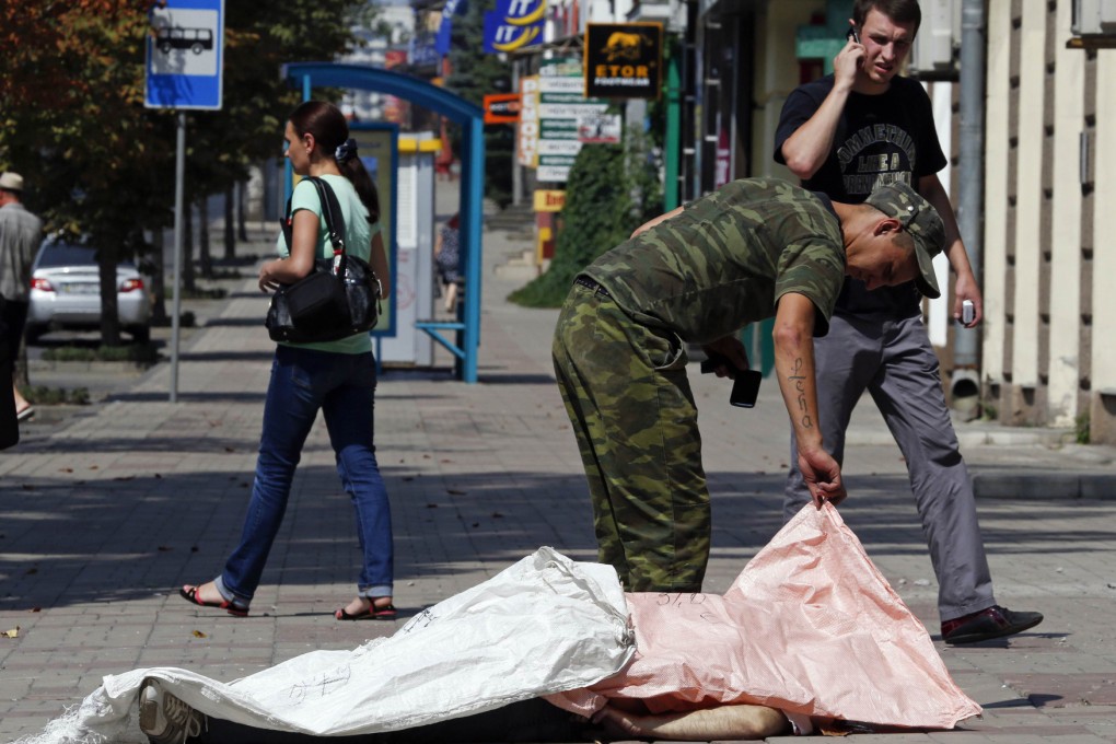 A pro-Russian separatist looks at victim in Donetsk. Photo: Reuters