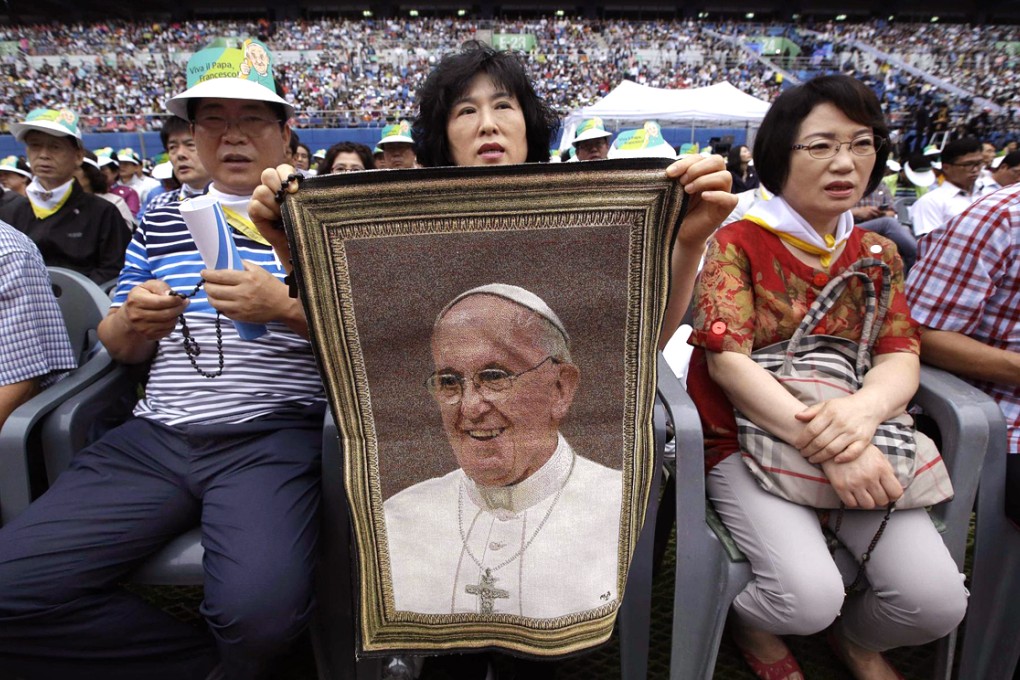 A woman holds a picture of Pope Francis before the mass. Photo: AFP