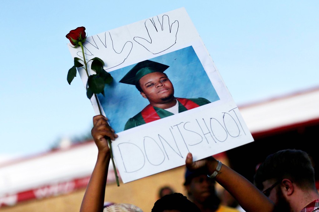 A demonstrator in Ferguson holds a sign with a picture of Michael Brown, who was shot dead by a white police officer. Photo: AFP