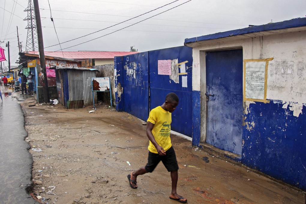 A Liberian man walks past an elementary school in West Point. The school was temporarily being used as an isolation unit for Ebola patients when it was attacked. Photo: EPA