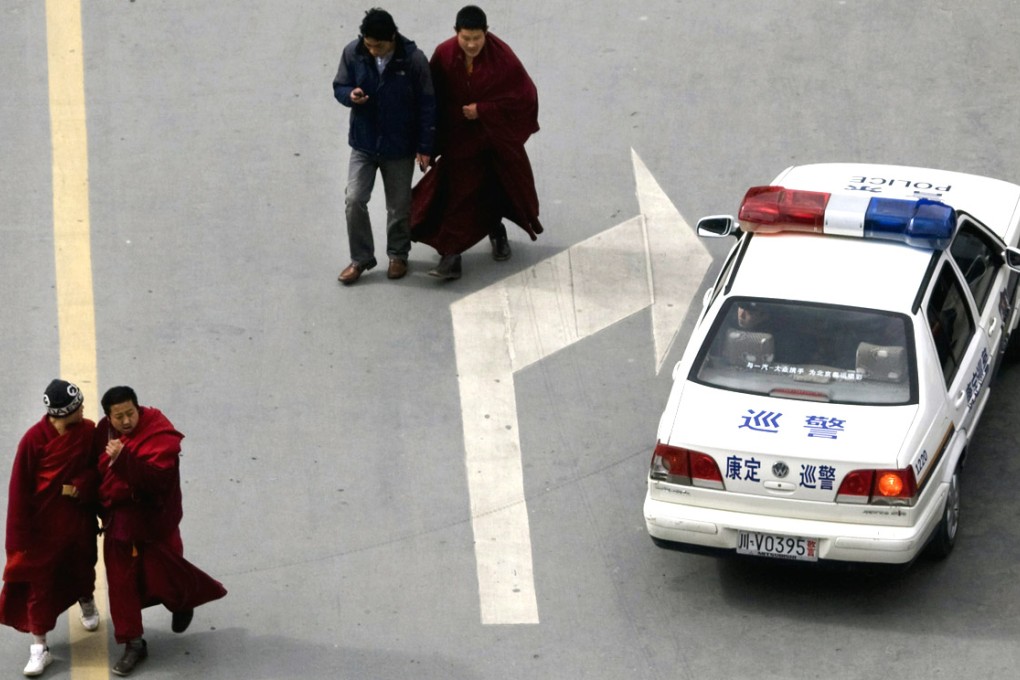 A policeman in a patrol car looks out at Tibetan monks on the streets of Kangding, Ganzi prefecture. Ganzi was the site of a bloody dispersal of protesters, according to rights groups. Photo: AP