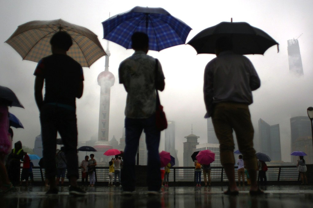 People stand under heavy rain at the Bund in front of the financial district of Pudong, downtown Shanghai on August 18, 2014. Photo: Reuters
