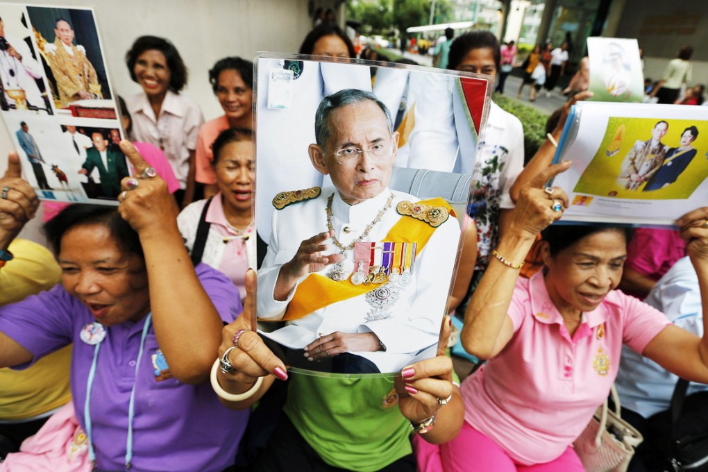 Thai well-wishers hold up photographs of King Bhumibol Adulyadej as they wait for his departure at Siriraj Hospital in Bangkok on August 6, 2014. Photo: EPA