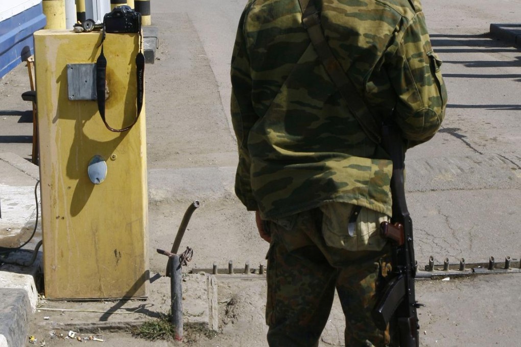 A pro-Russia fighter watches as the trucks cross the Ukrainian border yesterday. Photo: AFP