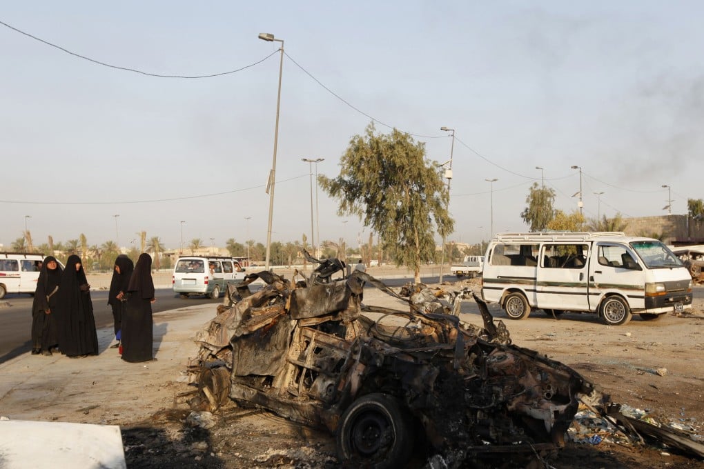 Iraqi women stand near the wreckage of a car bomb attack earlier this week. Photo: Reuters
