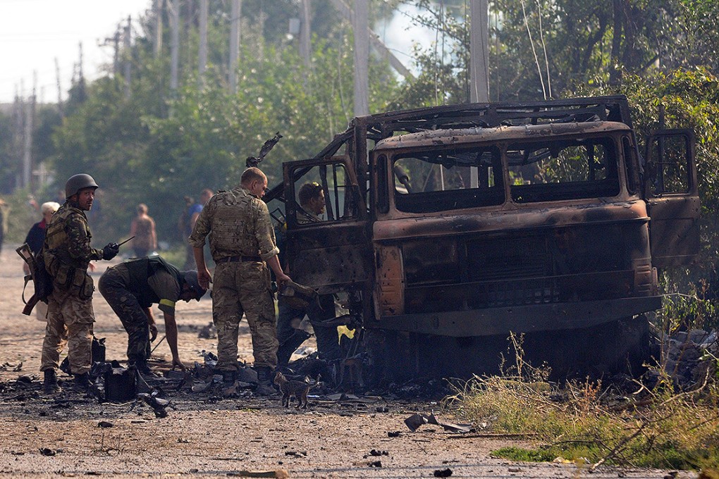 Ukrainian Donbass battalion fighters inspect their burnt out vehicle after after pro-Russian rebel shelling in Ilovaysk, 50km from Donetsk. Photo: EPA