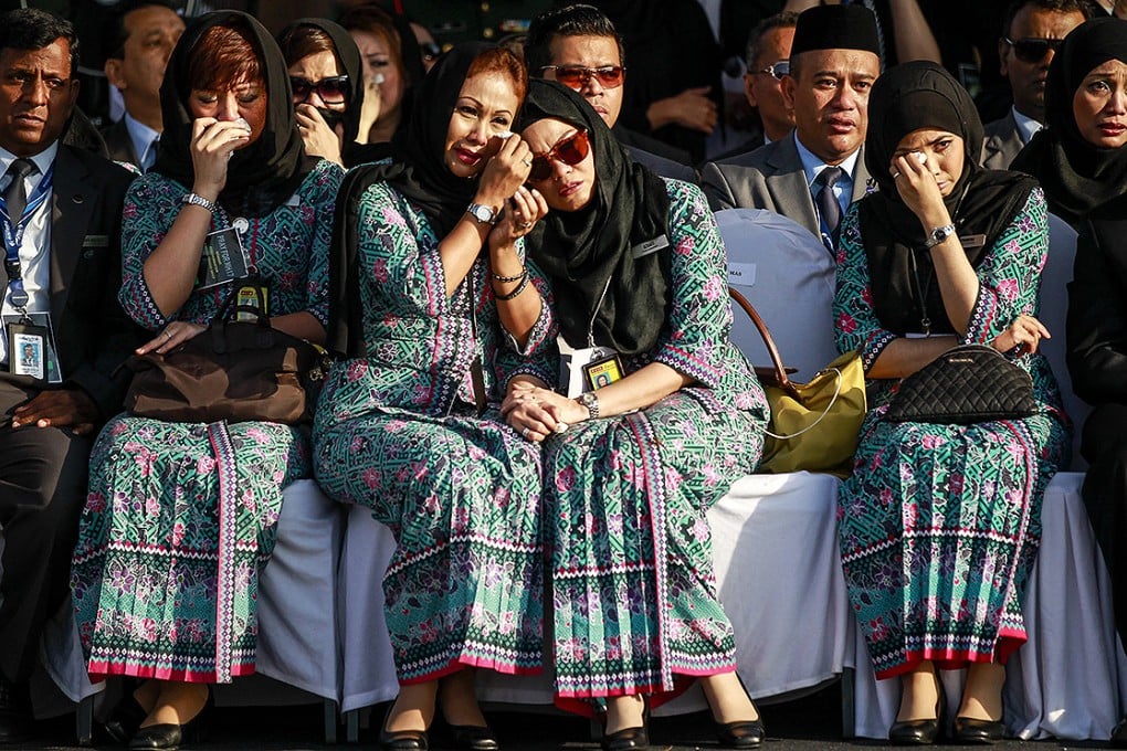 Malaysia Airlines crew members cry as an aircraft carrying the victims of the MH17 plane crash arrives at the Kuala Lumpur International Airport. Photo: EPA