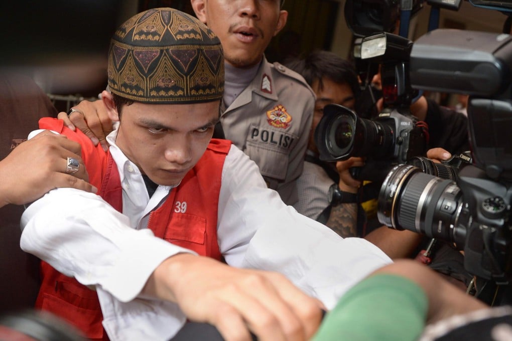 Cleaner Agun Iskandar is guarded by police ahead of his trial on sexual assault charges. Other cleaners face charges. Photo: AFP