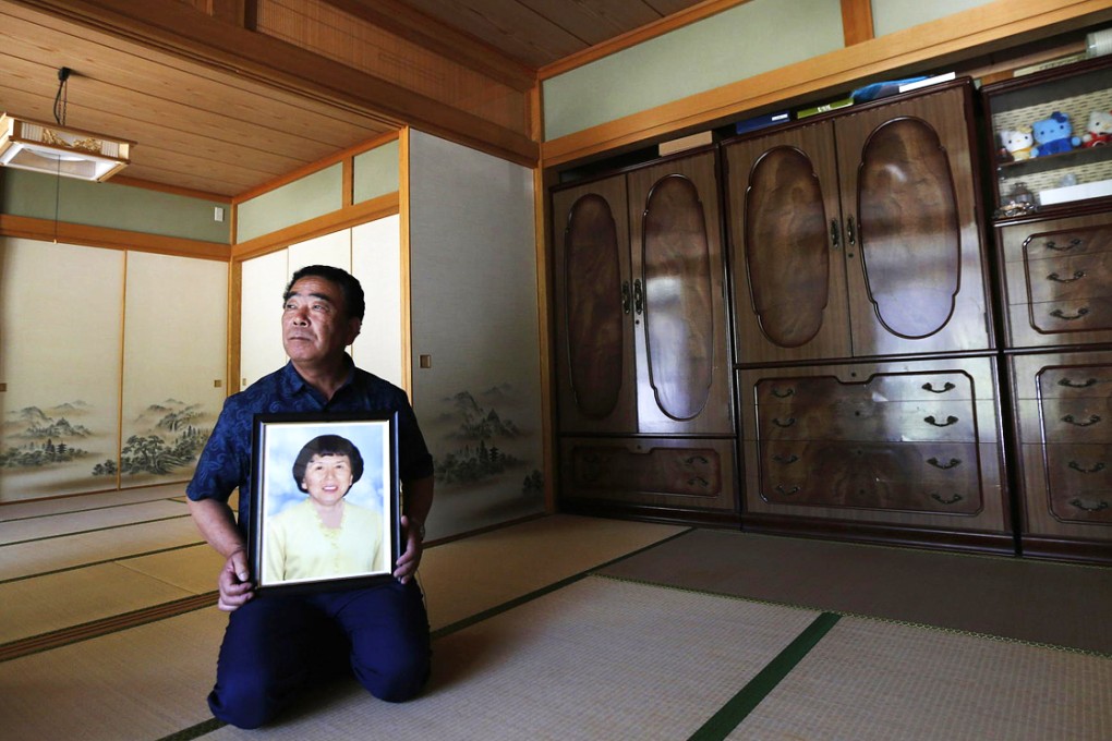 Mikio Watanabe holds a portrait of his late wife Hamako, who committed suicide after the Fukushima Daiichi nuclear disaster. Photo: Reuters