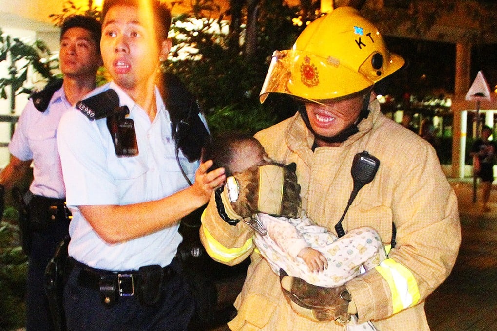 A firefighter cradles eight-month-old Chan Hoi-yee, who was rescued  from the scene of the blaze. Photo: SCMP