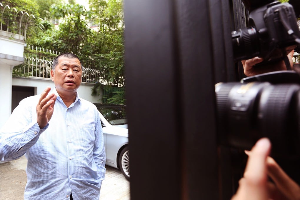 Jimmy Lai greets reporters and camera crews outside his home after a visit from ICAC officers. Photo: Sam Tsang