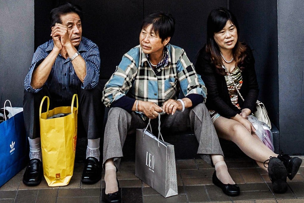 Mainland shoppers sit in front of a shop selling luxury goods in Hong Kong. Photo: AFP