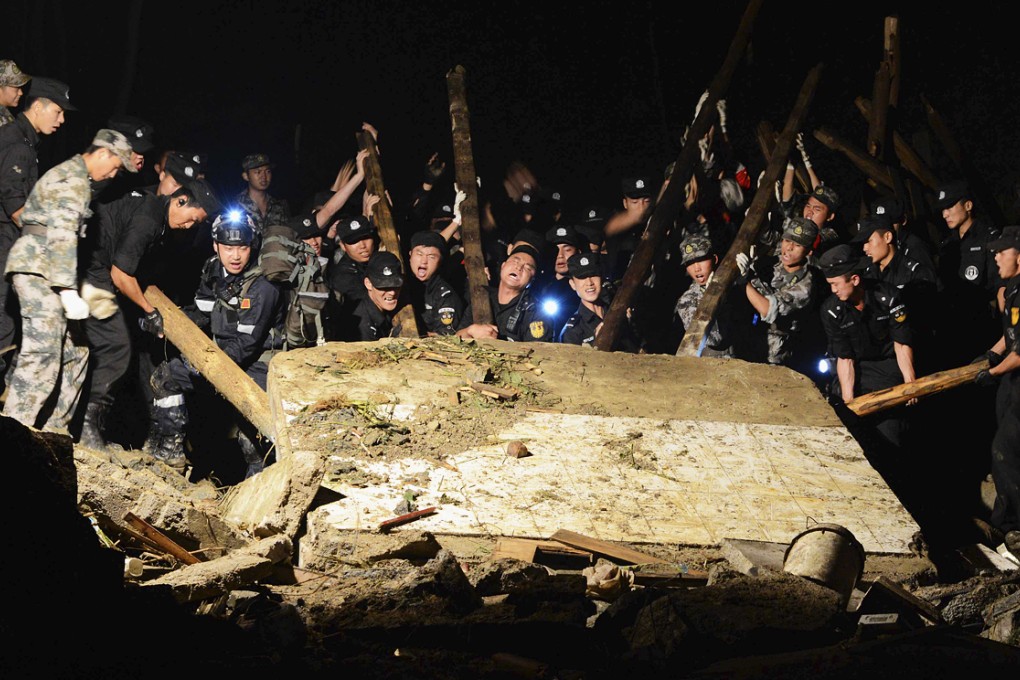 Rescue workers try to lift up a huge slab of rock as they search for survivors after a landslide destroyed two villages in Fuquan, Guizhou province. Photo: Reuters