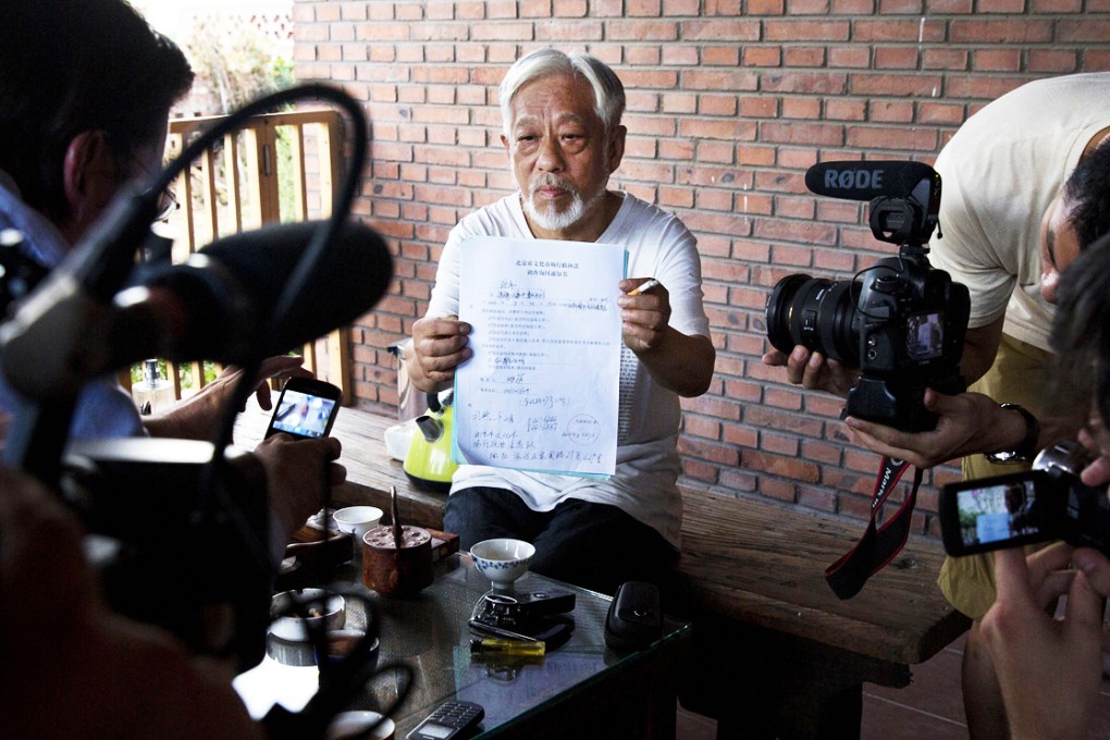 Beijing Independent Film Festival organiser Li Xianting holds up documents from the authorities after his release in Beijing. Photo: AP