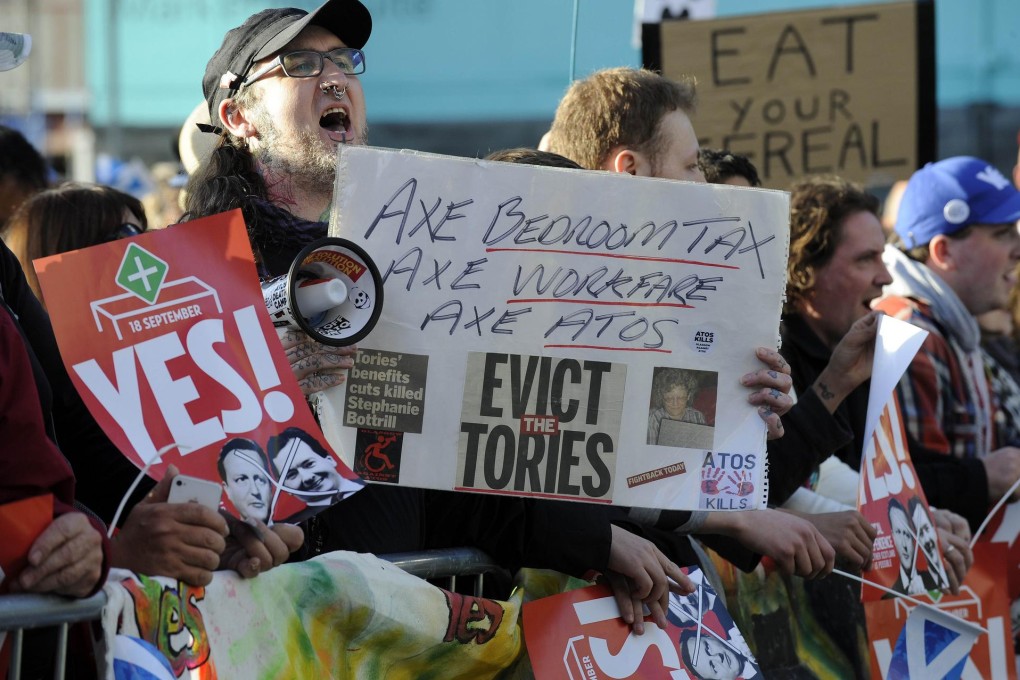 Protesters hold banners at David Cameron's Glasgow visit. Photo: AFP