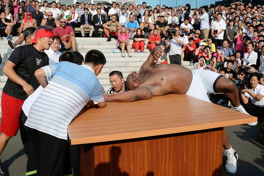 American martial artist Bob Sapp arm-wrestles with North Korean children ahead of a pro wrestling event in Pyongyang. Photo: Kyodo