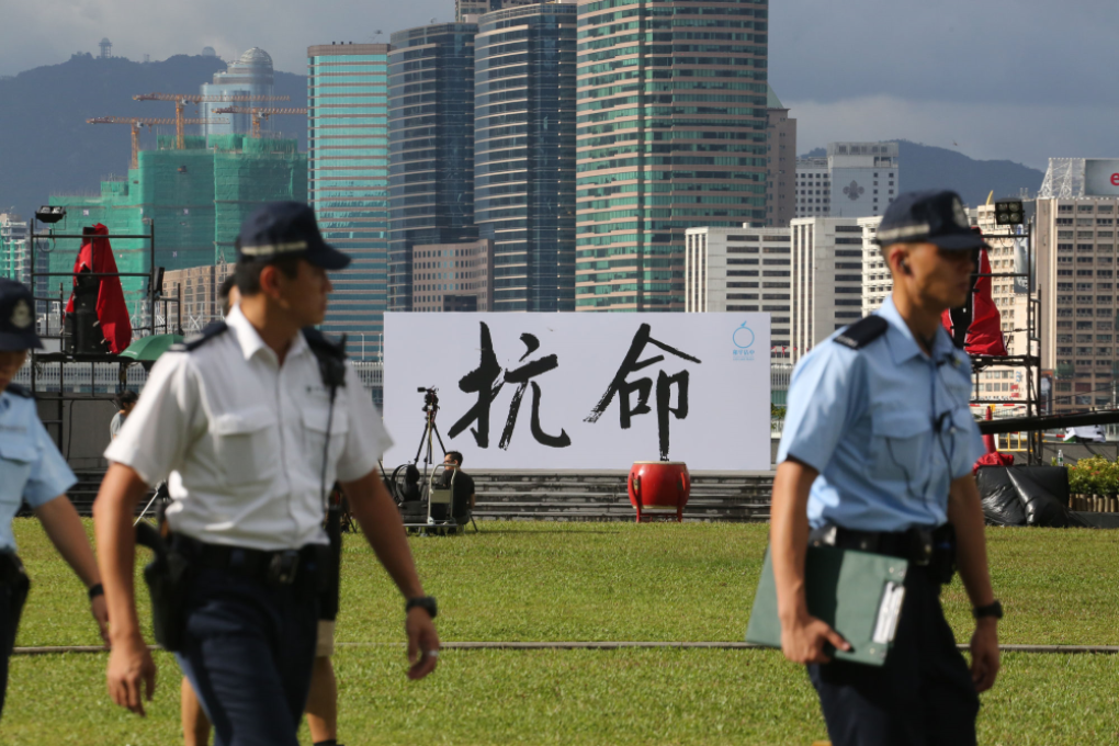 Police officers walk past a billboard with the Chinese characters kang ming, or "disobedience," erected by the Occupy Central campaign, near Hong Kong's Central district on Aug. 31, 2014. Photo: Felix Wong