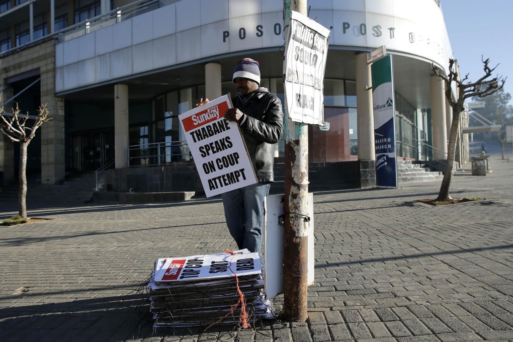 A worker hangs news posters about the coup. Photo: Reuters