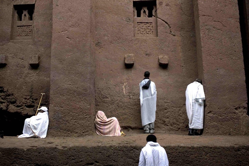 Orthodox Christian pilgrims pray by a wall at Bet Medhane Alem rock church in Lalibela.Photo: Reuters