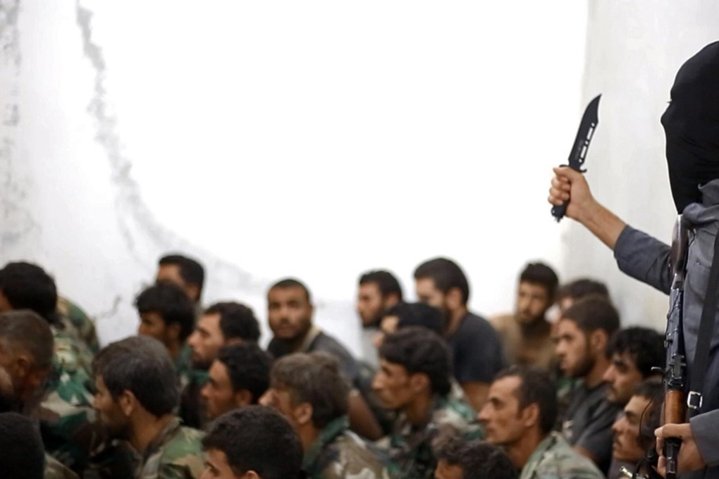 In this photo posted by Islamic State, a knife-wielding militant stands beside a group of Syrian soldiers captured in the battle for Syria's Tabqa air base. Photo: AP