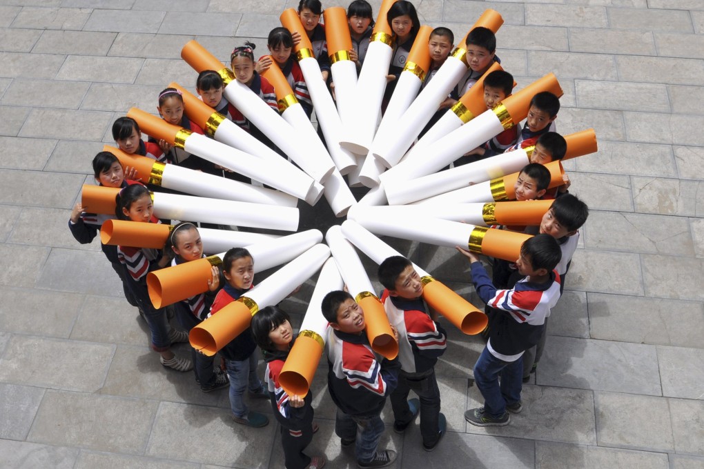 Students pose for pictures with "big cigarette models" during a campaign ahead of the World No Tobacco Day, at a primary school in Handan, Hebei province, May 29, 2013. Photo: Reuters