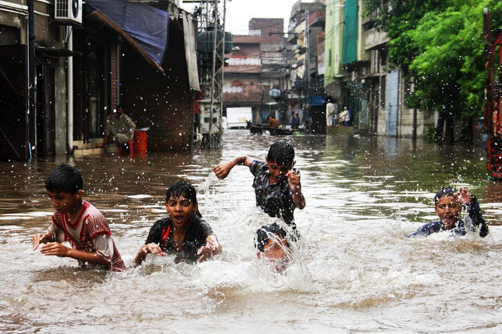 Children walk on the flooded street in eastern Lahore. Photo: Xinhua