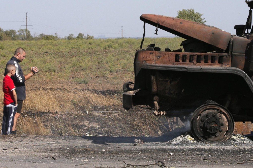 Residents film a still smouldering truck in Mariupol. Photo: EPA
