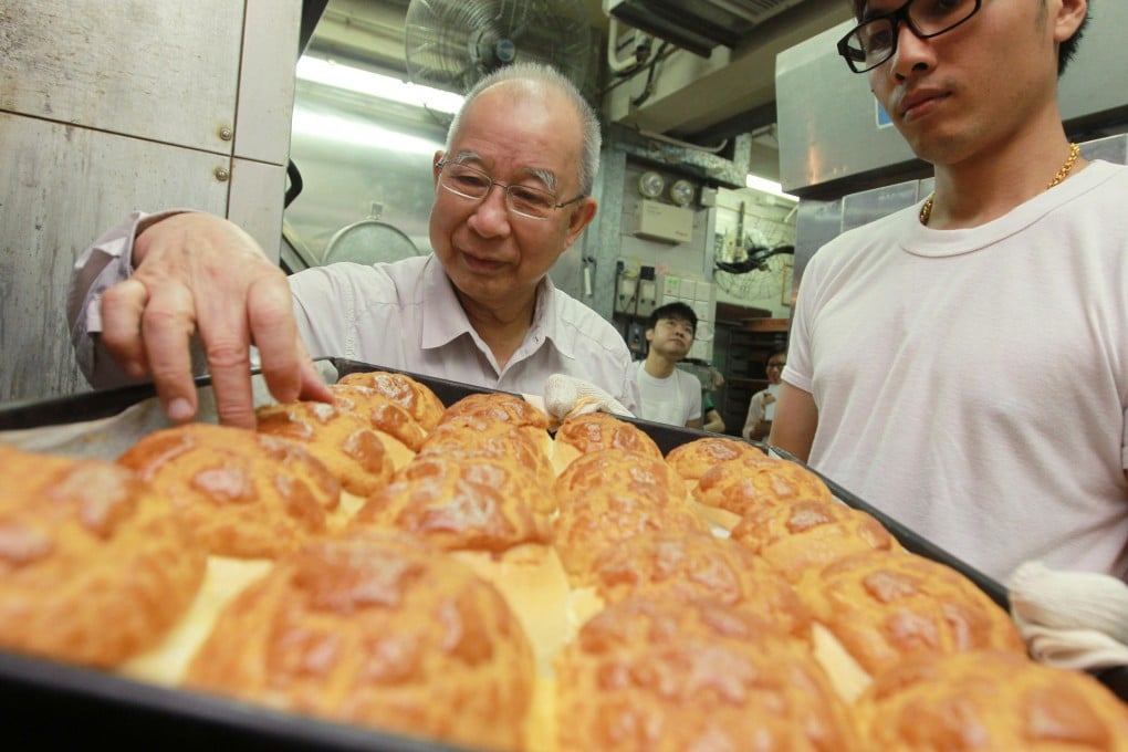 Tse Ching-yuen (left) checks out a batch of freshly baked pineapple buns at his 71-year-old Tai Tung Bakery in Yuen Long. Photo: Edward Wong